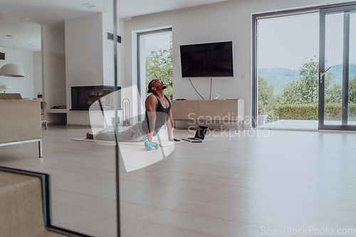 Image of Training At Home. Sporty man doing training while watching online tutorial on laptop, exercising in living room, free space