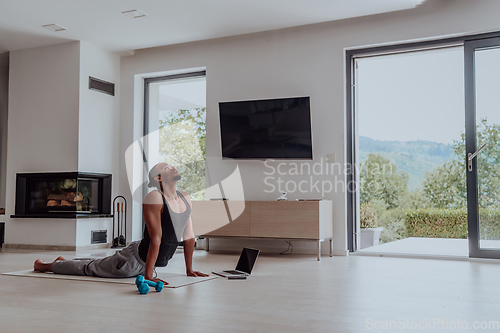 Image of Training At Home. Sporty man doing training while watching online tutorial on laptop, exercising in living room, free space