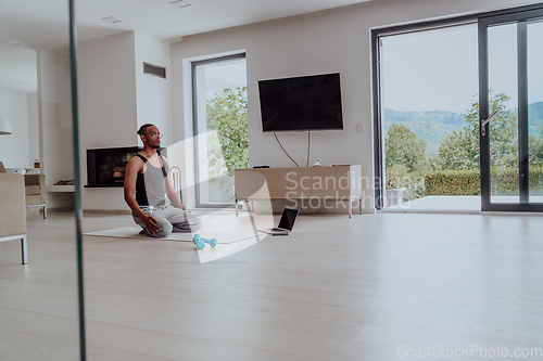 Image of Training At Home. Sporty man doing training while watching online tutorial on laptop, exercising in living room, free space