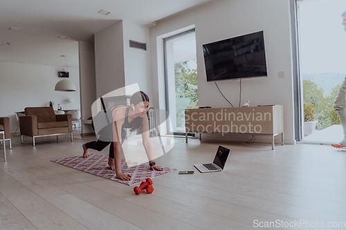 Image of Young Beautiful Female Exercising, Stretching and Practising Yoga with Trainer via Video Call Conference in Bright Sunny House. Healthy Lifestyle, Wellbeing and Mindfulness Concept.