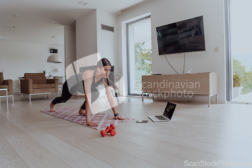 Image of Young Beautiful Female Exercising, Stretching and Practising Yoga with Trainer via Video Call Conference in Bright Sunny House. Healthy Lifestyle, Wellbeing and Mindfulness Concept.