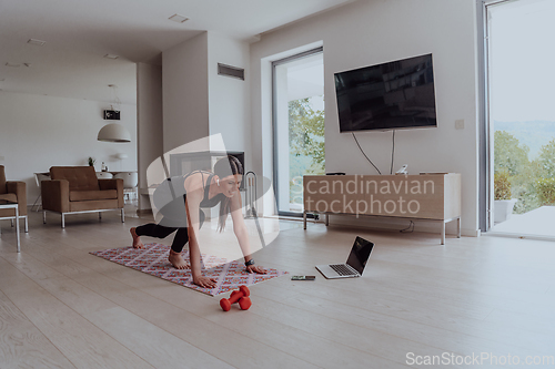 Image of Young Beautiful Female Exercising, Stretching and Practising Yoga with Trainer via Video Call Conference in Bright Sunny House. Healthy Lifestyle, Wellbeing and Mindfulness Concept.