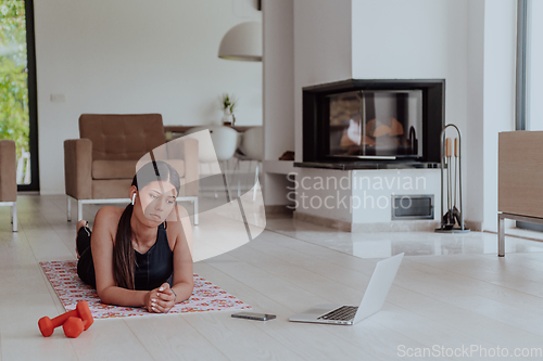 Image of Young woman resting after online training while lying on the living room floor