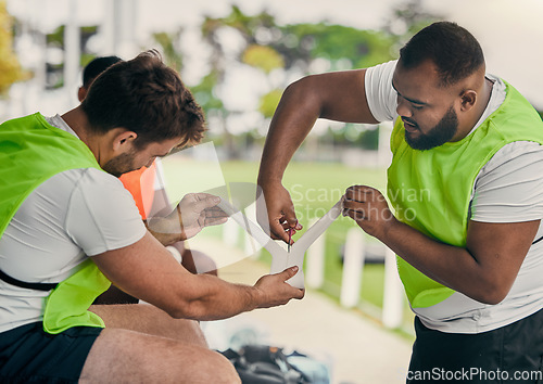 Image of Men, cutting bandage or rugby team on fitness break, exercise workout or training in a sports game. Preparation, friends or group of people in practice match with tape, strap or wrap on stadium bench