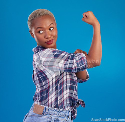 Image of Young black woman flex arms in studio, blue background and backdrop of freedom, empowerment or pride. Female model, bicep and girl power in fight for gender equality, strong muscle or feminism leader