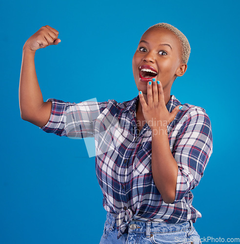 Image of Shocked, arm flex and portrait of black woman in studio for empowerment, confident or success. Achievement, hard work and pride with female isolated on blue background for power, strong or motivation