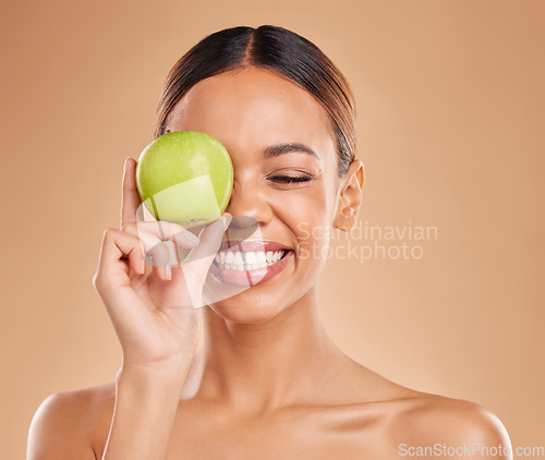 Image of Beauty, skincare or happy woman with apple in studio on beige background for healthy nutrition or clean diet. Smile, face or girl model laughing or marketing natural fruits for vitamins or wellness