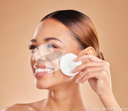 Image of Cotton, beauty and cleaning skin of woman in studio for dermatology, cosmetic and detox. Face and smile of female with hand for natural facial makeup clean, self care and skincare on brown background