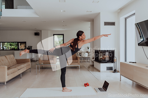 Image of Young Beautiful Female Exercising, Stretching and Practising Yoga with Trainer via Video Call Conference in Bright Sunny House. Healthy Lifestyle, Wellbeing and Mindfulness Concept.