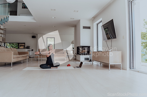 Image of Young Beautiful Female Exercising, Stretching and Practising Yoga with Trainer via Video Call Conference in Bright Sunny House. Healthy Lifestyle, Wellbeing and Mindfulness Concept.