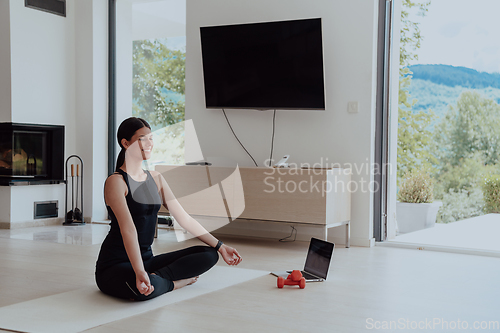 Image of Young Beautiful Female Exercising, Stretching and Practising Yoga with Trainer via Video Call Conference in Bright Sunny House. Healthy Lifestyle, Wellbeing and Mindfulness Concept.