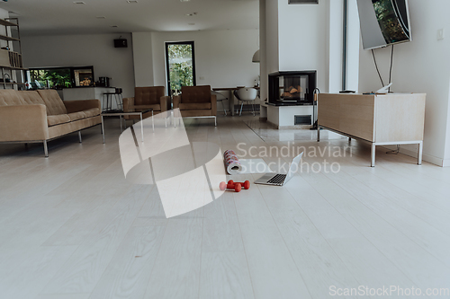 Image of Photo of a laptop, dumbbells and headphones on the floor of the living room. Online training concept