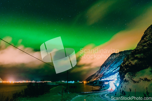 Image of Amazing display of northern lights seen in the north with a bright green band dancing across the sky with a stunning log cabin lodge below.