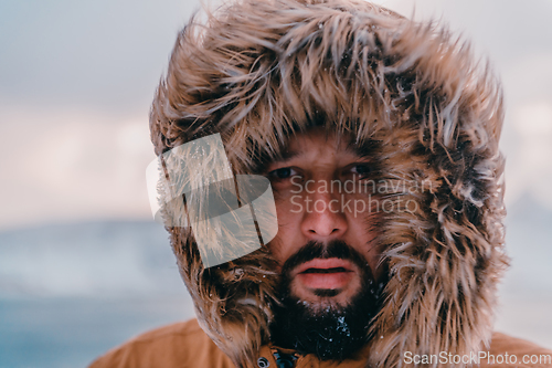 Image of Headshot photo of a man in a cold snowy area wearing a thick brown winter jacket and gloves. Life in cold regions of the country.