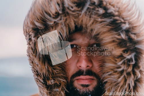 Image of Headshot photo of a man in a cold snowy area wearing a thick brown winter jacket and gloves. Life in cold regions of the country.