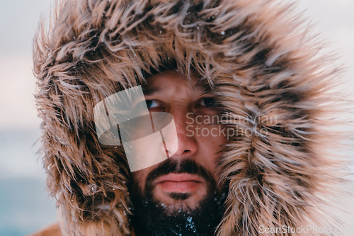 Image of Headshot photo of a man in a cold snowy area wearing a thick brown winter jacket and gloves. Life in cold regions of the country.