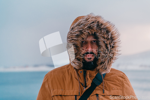 Image of Headshot photo of a man in a cold snowy area wearing a thick brown winter jacket and gloves. Life in cold regions of the country.