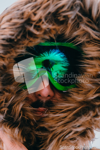 Image of Headshot photo of a man in a cold snowy area wearing a thick brown winter jacket, snow goggles and gloves. Life in cold regions of the country.