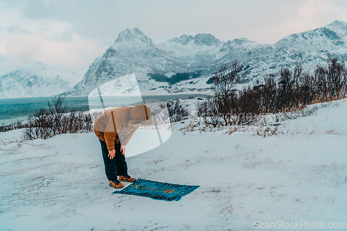 Image of A Muslim traveling through arctic cold regions while performing the Muslim prayer namaz during breaks