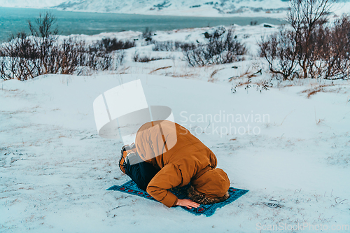 Image of A Muslim traveling through arctic cold regions while performing the Muslim prayer namaz during breaks