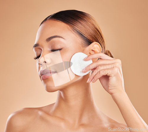 Image of Cleaning face, cotton and beauty of woman in studio with dermatology, cosmetic and detox. Aesthetic female with hand for natural facial makeup clean, self care and skincare glow on brown background