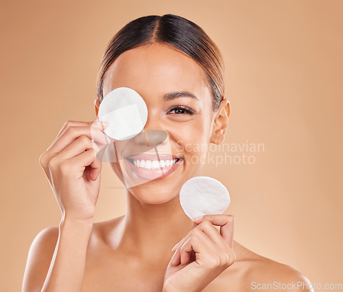 Image of Face, cotton pad and woman with skincare, cosmetics and glow against a brown studio background. Portrait, female and lady with makeup remover, foundation and organic facial with grooming or soft skin