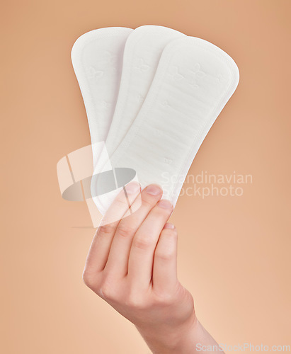 Image of Hand, sanitary pads and period with a woman in studio on a brown background for female hygiene or care. Lifestyle, and gynecology with a female holding a feminine product for her menstrual cycle