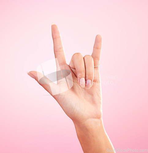 Image of Hands, closeup and woman in studio with rock and roll sign, gesture or symbol against pink background. Zoom, rebel and girl with rocker emoji for edgy, cool or contemporary, metal or punk aesthetic