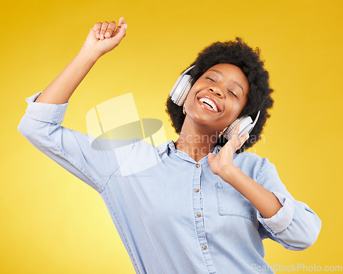 Image of Black woman, dancing with headphones and freedom, music and happiness on yellow studio background. Happy female, carefree and dance along to radio, audio streaming with fun and energy with technology