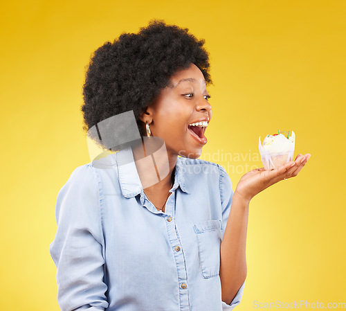 Image of Black woman, cupcake and excited or happy in studio while eating sweet food on a yellow background. African female model with snack, dessert or cake for happiness, birthday or celebration mockup