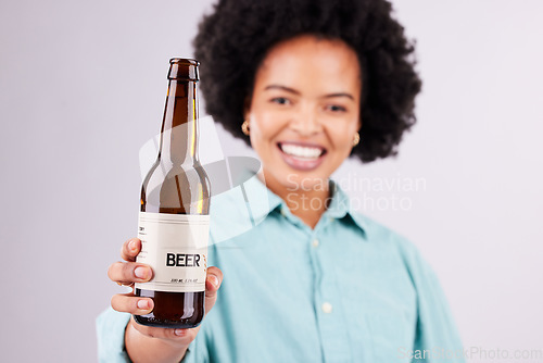 Image of Hand, beer and advertising with a black woman in studio on a gray background for alcohol promotion. Portrait, bottle and beverage with a female holding a product for celebration or congratulations