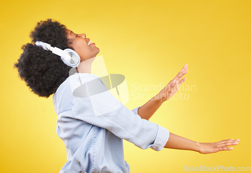 Image of Black woman, dance with headphones and freedom, music and happiness on yellow studio background. Happy female, carefree and dancing along to radio, audio streaming with fun and energy with technology