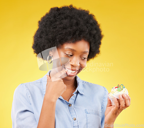 Image of Woman, cupcake and studio with thinking, diet and temptation for guilt with junk food by yellow background. African model, cake and choice for unhealthy, nutrition and sweets with discipline for meal