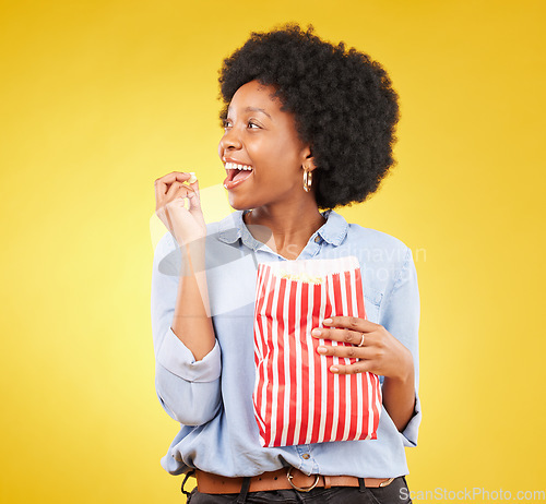 Image of Happy, eating and popcorn with black woman in studio for movie, streaming service and cinema. Television, smile and theatre with female and snack isolated on yellow background for food, tv and film