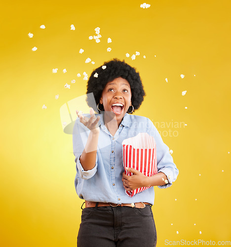 Image of Happy, throwing and popcorn with black woman in studio for movie, streaming service and cinema. Laugh, funny and theatre with female and snack isolated on yellow background for food, tv and film