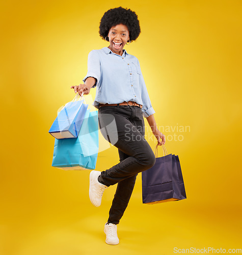 Image of Black woman with shopping bag, happy with fashion and retail in portrait on yellow studio background. Happiness, female with discount and sale at boutique with designer brand, carefree and mockup