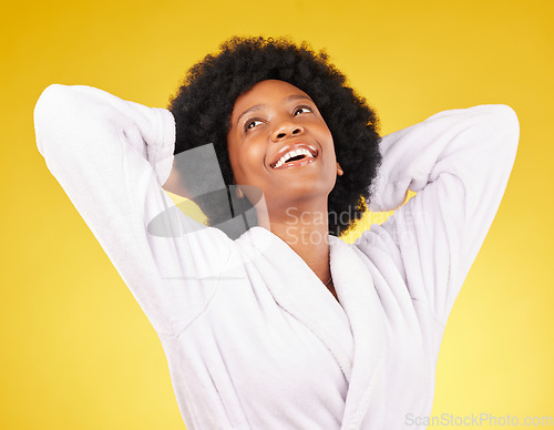 Image of Black woman relax, bathrobe and happiness in a studio ready for luxury spa treatment for self care. Isolated, yellow background and happy young female with a smile from skincare and wellness