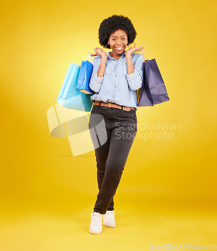 Image of Black woman with shopping bag, smile with fashion and retail in portrait on yellow studio background. Happiness, female with discount and sale at boutique with designer brand, happy and mockup space