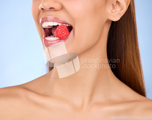 Image of Mouth, beauty and strawberry with a model woman in studio on a blue background closeup biting a fruit. Food, health and nutrition with a female eating a berry for antioxidants or diet benefits