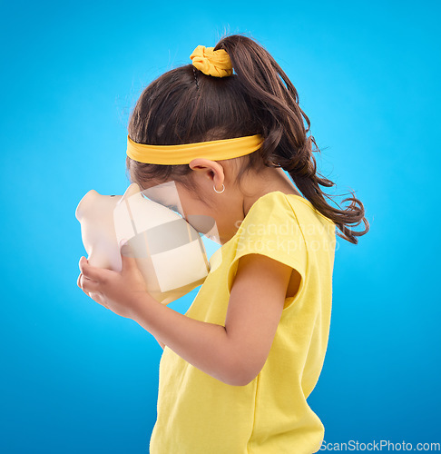 Image of Child, holding and piggy bank in studio for finance, planning and future investment against blue background. Money, box and girl with financial, savings and growth, invest and management learning