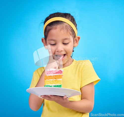 Image of Food, happy and child with rainbow cake on blue background for birthday, celebration and party mockup. Comic, smile and excited young girl with sweet snack in studio with pastry, dessert and eating