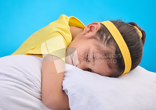 Image of Calm young girl, pillow and sleep in a studio feeling tired, fatigue and ready for dreaming. Isolated, blue background and happy little child with pillows and closed eyes for sleeping, rest and nap