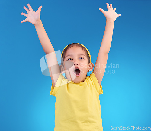 Image of Child, goal cheer and studio with a little girl feeling happy with energy and celebration. Isolated blue background and young kid with arms in the air cheering crazy and yelling with happiness