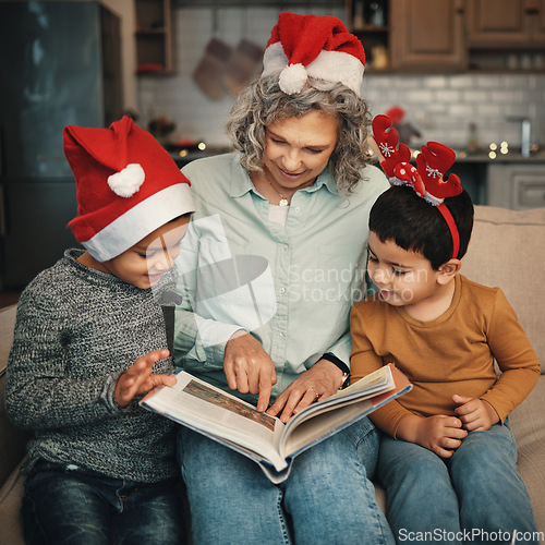 Image of Christmas, books or reading with a grandmother and kids looking at photographs during festive season. Family, love or celebration with a senior woman and grandchildren holding a story book