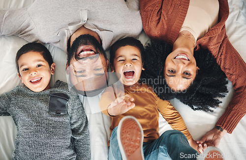 Image of Laughing, above and portrait of a family on a bed for relaxation, bonding and quality time. Playful, smile and carefree parents with children in the bedroom to relax and play in the morning together