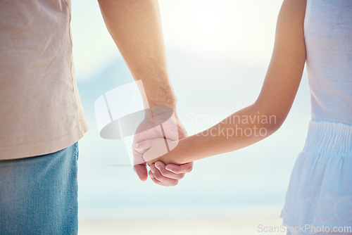 Image of Holding hands, family or children with a father and daughter outdoor together at the beach during summer. Kids, love or trust with a man and female child standing outside for bonding during the day