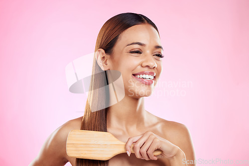 Image of Woman, brush and hair care smile in studio for salon, hairdresser or shine shampoo or treatment. Hairstyle of a happy beauty model on a pink background for color or growth cosmetics and grooming