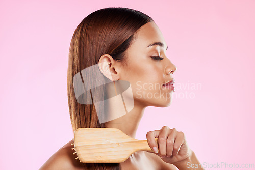 Image of Woman, brushing hair and hairbrush beauty profile in studio for salon or hairdresser shine shampoo. Haircare of a aesthetic model on a pink background for color, glow or growth cosmetics and grooming