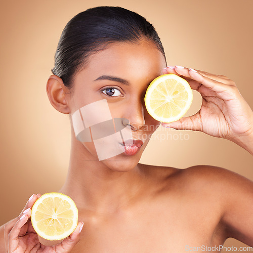 Image of Indian woman, beauty and skincare with lemon in studio for health, wellness or fruit by brown background. Asian model girl, young or happy with natural citrus fruits for health, cosmetic or skin glow