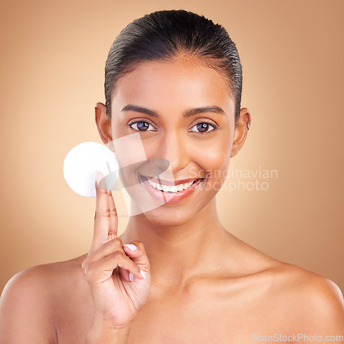 Image of Beauty, skincare and cotton with portrait of indian woman in studio for self care, makeup remover and cosmetics. Happy, clean and glow with model on brown background for results, natural and facial